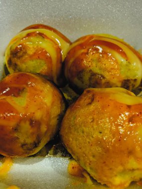 Beyaz köpükle servis edilen dört Takoyaki yakın plan.