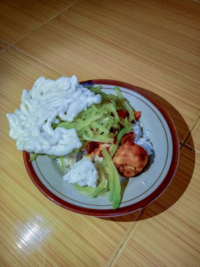 A delicious dish of white rice, chayote vegetables, white crackers and chicken sambal on a plate, tiled floor in the background. Indonesian home cooking clipart