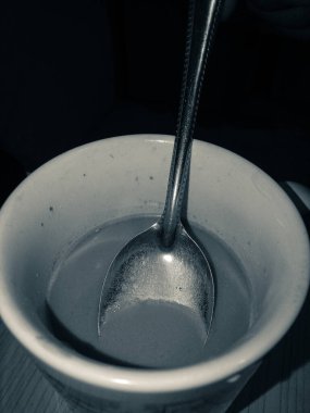 Bu yukarıdan çekilmiş, üstünde kaşık olan bir fincan sıcak çikolatalı sütün monokrom fotoğrafı..