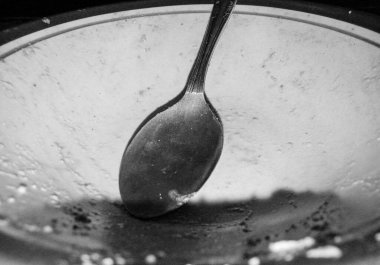 Kirli bir kase ve bir kaşık çok önemlidir. Görüntü daha sonra kasenin nasıl temizleneceğini gösteriyor. Tek renkli, siyah beyaz