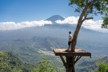 İnsan gezgin Bali adasında tatilin tadını çıkarır, Agung volkanı ile görüş açısında durur.