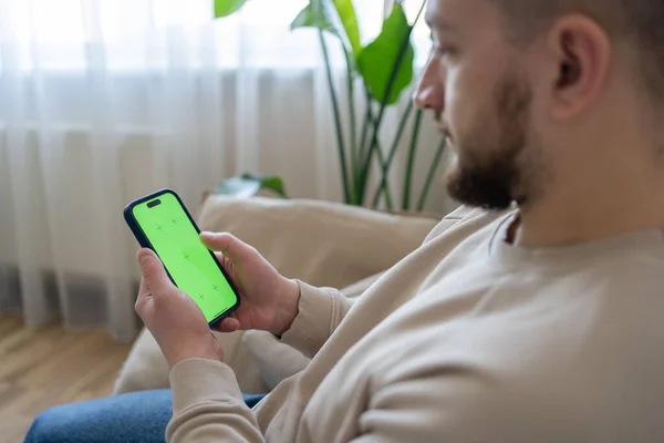 Uomo Casa Sdraiato Divano Utilizzando Smartphone Con Schermo Modello Verde — Foto Stock