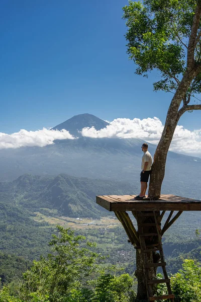 男旅行者はバリ島での休暇を楽しみアグン火山との視点に立つ — ストック写真