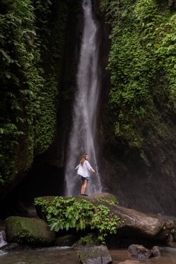 Tropikal ormanda şelale ve yalnız kadın turist. Endonezya, Bali 'de Leke Leke şelalesi.