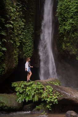 Tropikal ormanda şelale ve yalnız kadın turist. Endonezya, Bali 'de Leke Leke şelalesi.