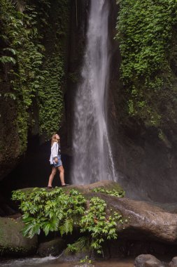 Tropikal ormanda şelale ve yalnız kadın turist. Endonezya, Bali 'de Leke Leke şelalesi.