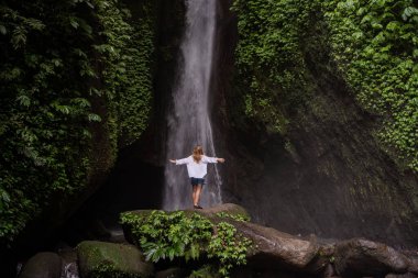 Tropikal ormanda şelale ve yalnız kadın turist. Endonezya, Bali 'de Leke Leke şelalesi.