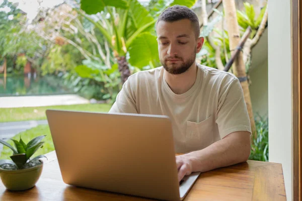 Young man using a laptop computer in a garden . business, study, freelance