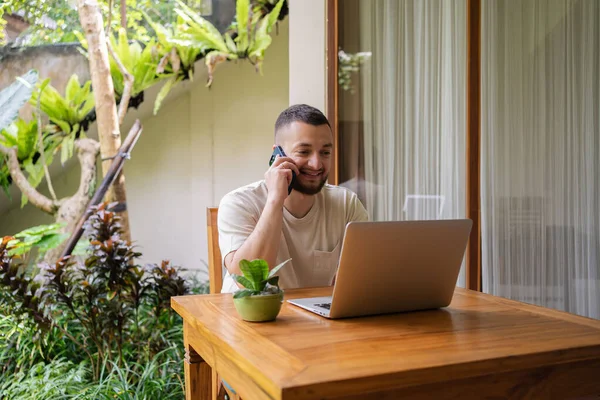 Freelancer çalışanı telefonla konuşuyor, dizüstü bilgisayar kullanıyor, ekrana bakıyor, girişimci yöneticiye telefonla danışıyor, bilgisayar ekranına bakıyor, projeyi tartışıyor, bilgi okuyor..