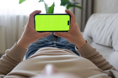 Evdeki Adam, Smartphone kullanarak Green Mock-up Screen, Swiping, Scrolling Jestleri yapıyor. Cep Telefonu Kullanan Adam, İnternet Sosyal Ağ Taraması