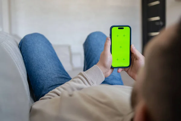 Mężczyzna Domu Spoczywa Kanapie Przy Użyciu Smartfona Zielonym Ekranem Makiety — Zdjęcie stockowe