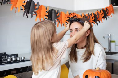 Anne ve küçük kız evde Cadılar Bayramı hazırlıkları sırasında oynuyorlar ve eğleniyorlar.. 