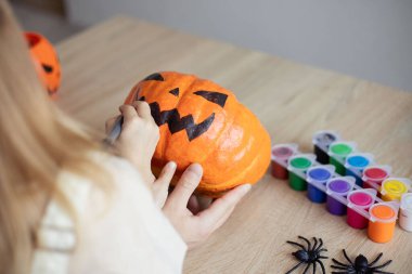 Küçük kız evde babasıyla Cadılar Bayramı süsü hazırlıyor, balkabağına korkunç bir yüz çiziyor ve tatil hazırlıklarının keyfini çıkarıyor.