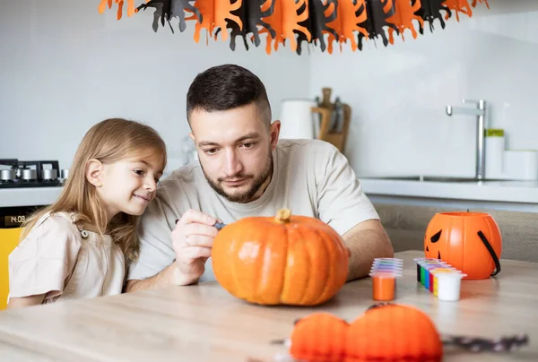 Mutlu aile babası ve kızı birlikte Cadılar Bayramı dekorasyonu yapıyorlar.