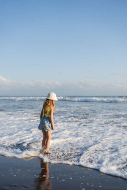 Gün batımında sahilde atlayan ve koşan genç bir kız.