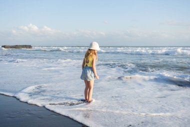 Gün batımında sahilde atlayan ve koşan genç bir kız.