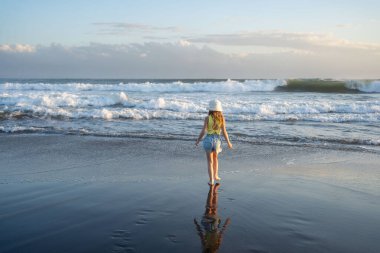 Gün batımında sahilde atlayan ve koşan genç bir kız.