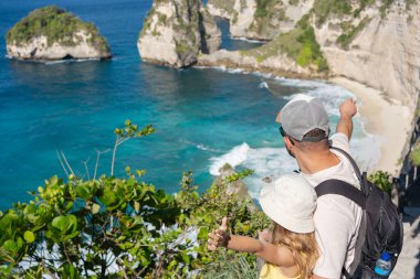 Çocuklu bir adam, Endonezya, Asya 'daki Bali adası yakınlarındaki Nusa Penida adasında elmas plajını keşfediyor..