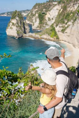 Çocuklu bir adam, Endonezya, Asya 'daki Bali adası yakınlarındaki Nusa Penida adasında elmas plajını keşfediyor..