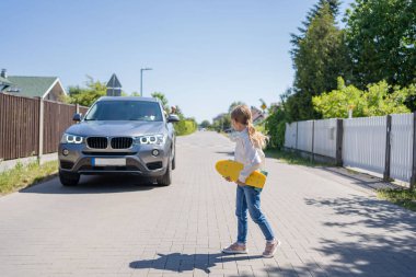 Yoldan geçen kaykaylı kız, arabaya bakmıyor.