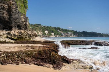 Kayalık dağları olan bir kumsal ve güneşli bir günde Hint okyanusunun berrak suları. . 