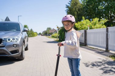 Kazayla oldu. Scooter süren küçük bir kız ve bir arabanın önünde karşıdan karşıya geçiyor..