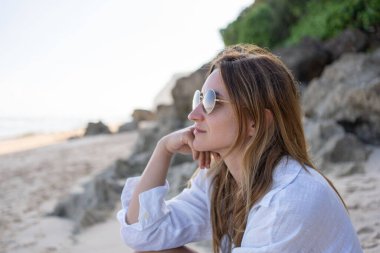 Kumsalda tek başına oturan genç kadın, rahatla ve doğanın tadını çıkar.