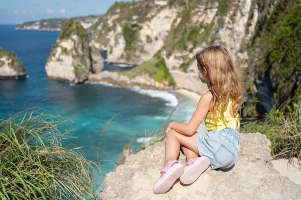 Diamond Beach 'e bakan uçurumun kenarındaki çocuk Nusa Penida. Nusa Penida Bali, Endonezya 'daki Elmas Sahili manzarası.