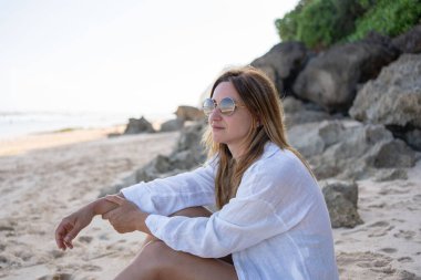 Kumsalda tek başına oturan genç kadın, rahatla ve doğanın tadını çıkar.