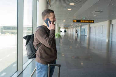  Havaalanında cep telefonuyla konuşan bir adamın portresi, terminalde uçmayı beklerken telefonla konuşmaktan zevk alan bir adam.. 
