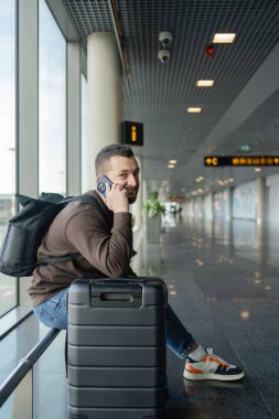  Havaalanında cep telefonuyla konuşan bir adamın portresi, terminalde uçmayı beklerken telefonla konuşmaktan zevk alan bir adam.. 