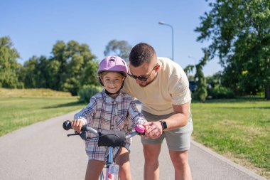 Baba öğretim kız binmek bisiklet park için