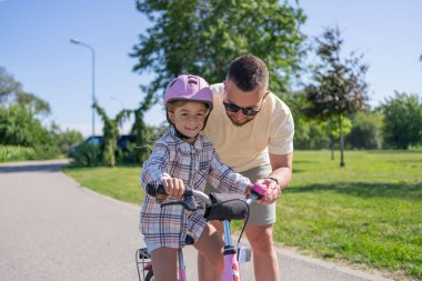 Baba öğretim kız binmek bisiklet park için