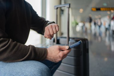 Turist bekleme salonunda yerini almakla meşgul. Havaalanında uçak beklerken cep telefonlu genç bir adam.
