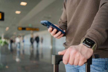 Turist bekleme salonunda yerini almakla meşgul. Havaalanında uçak beklerken cep telefonlu genç bir adam.