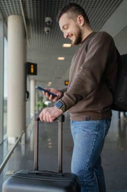 Turist bekleme salonunda yerini almakla meşgul. Havaalanında uçak beklerken cep telefonlu genç bir adam.