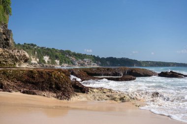 Kayalık dağları olan bir kumsal ve güneşli bir günde Hint okyanusunun berrak suları. . 