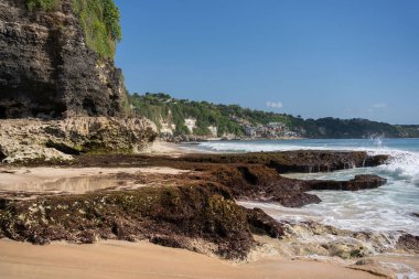 Kayalık dağları olan bir kumsal ve güneşli bir günde Hint okyanusunun berrak suları. . 