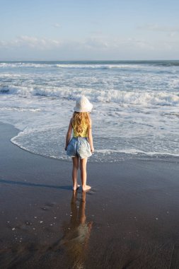 Çocuk Bali 'deki tropikal deniz sahillerinde eğleniyor. Sörf kenarındaki su birikintisinin yanında koşan komik kız. Aktif çocuk yaşam tarzı. 