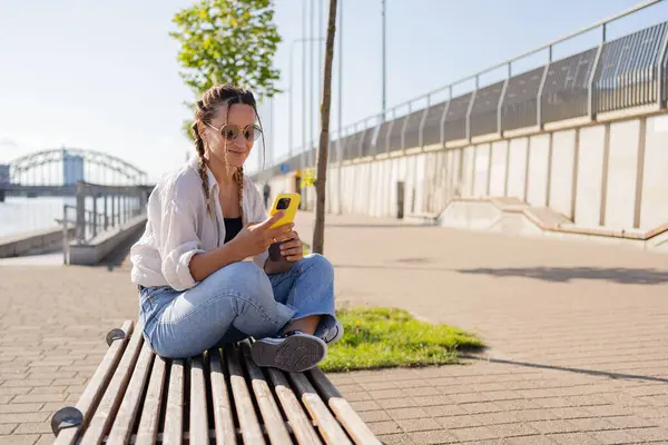 市街地に座っている若い女性ヒップスターは セロファンを使用し 友人とチャットし ビデオ通話を持っています — ストック写真