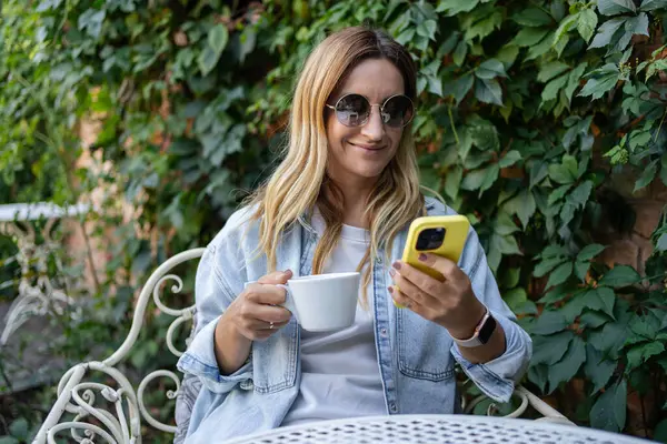 stock image woman sitting in cafe outside with mobile phone, freelance, chatting with friends, learning