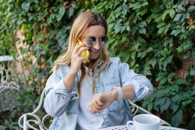  Kulaklık takan ve açık kafede oturup müzik dinleyen bir kadın. Restoranda uzaktan kumandalı çalışan serbest çalışan biri.. 