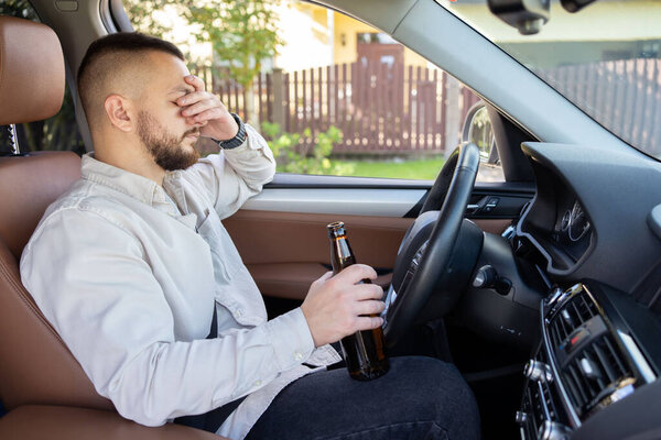 Мужчина пьет алкоголь за рулём машины. Не пить и не водить машину