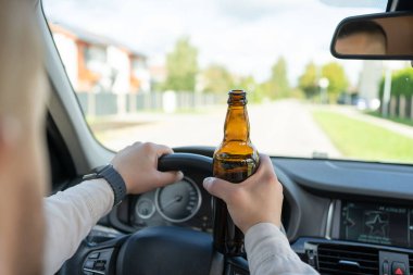 Elinde bir şişe alkolle araba süren sarhoş bir adam. Direksiyondaki şoför elinde bir şişe alkolün yakın çekimi var. Alkol kullanım konsepti