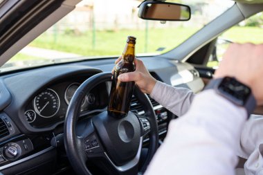 Elinde bir şişe alkolle araba süren sarhoş bir adam. Direksiyondaki şoför elinde bir şişe alkolün yakın çekimi var. Alkol kullanım konsepti