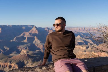 Büyük Kanyon 'un kenarında oturan yürüyüşçü, baharda Büyük Kanyon Ulusal Parkı' nda yürüyüş yapmanın tadını çıkarıyor.. 
