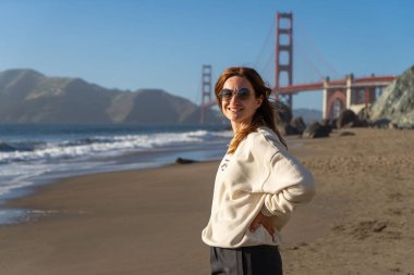 Sahilde yürüyen genç bir kadın Golden Gate, San Francisco 'ya bakıyor. . 