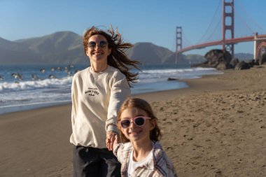 Anne ve kızı sahilde eğleniyor, kadınlara odaklanıyor.