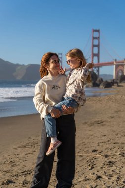 Anne ve kızı sahilde eğleniyor, kadınlara odaklanıyor.