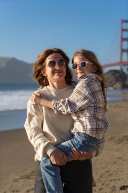 Anne ve kızı sahilde eğleniyor, kadınlara odaklanıyor.